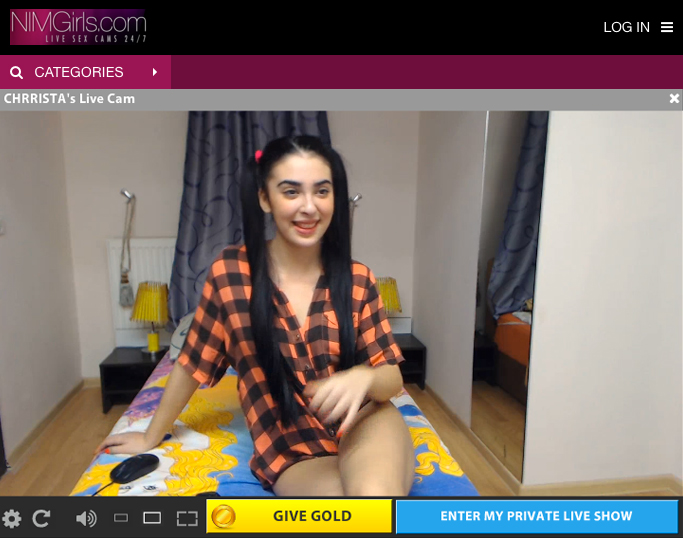 Screen shot of a webcam model live stream feed on the top paying cam model site. A pretty female model working the highest paying webcam model job is sitting on a bed smiling at the camera while wearing a pajama top.